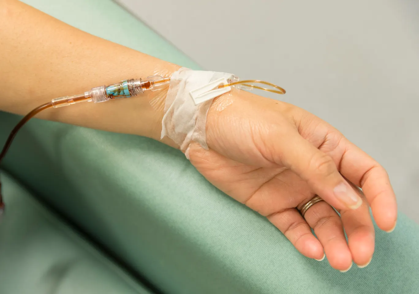 Kroplówki witaminowe Golub-Dobrzyń: dłoń z wenflonem i linią infuzyjną na podkładzie